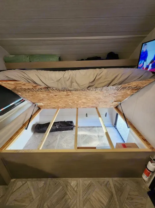 RV rental interior: Lift-up bed reveals spacious under-bed storage. Efficient design for travel and camping.. Other Other 2024