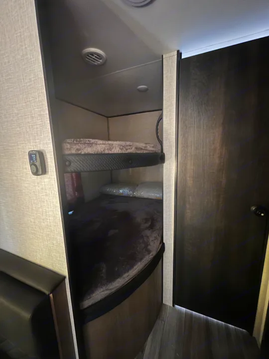 Comfortable bunk beds in an RV rental, offering a compact sleeping area with thermostat and ceiling vents.. Other Other 2024