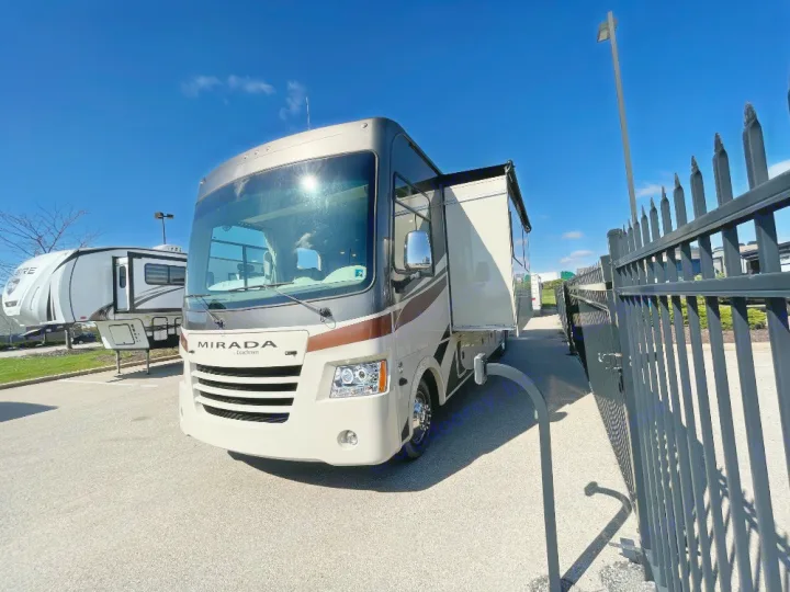 A large beige Mirada motorhome with an extended side and awning, parked at an RV lot. Explore this spacious RV rental!. Coachmen Mirada 2018