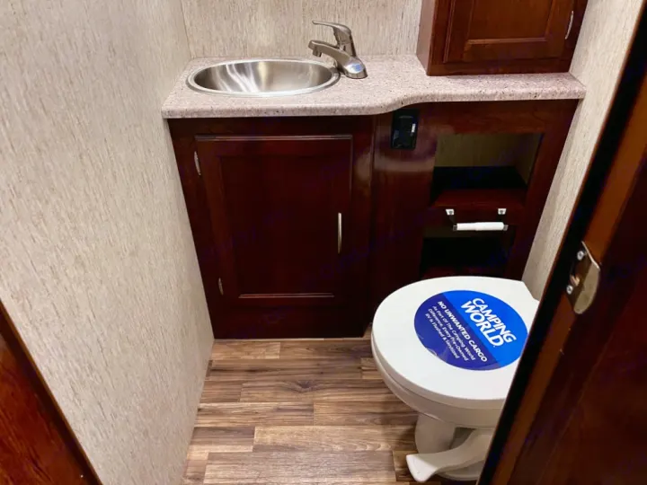 Compact RV rental bathroom features a sink, toilet, and storage, ready for your next adventure.. Coachmen Mirada 2018