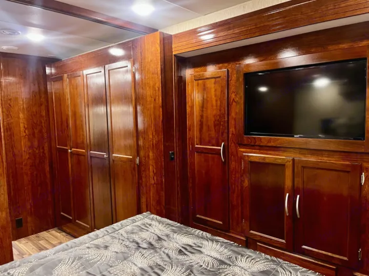 Spacious RV rental bedroom featuring rich wood cabinetry, a built-in TV, and ample storage. Perfect for travel.. Coachmen Mirada 2018