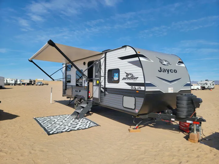 This Jayco Jay Flight Baja RV rental is set up with its awning out and a mat on the desert sand.. Jayco Jay flight 2024