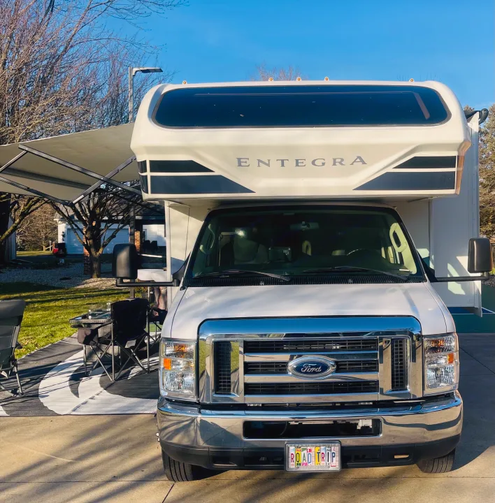 White Ford Entegra RV rental parked with extended awning and outdoor seating under clear skies, ready for adventure.. Entegra Coach Odyssey 2020