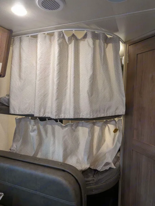 RV rental interior: two bunk beds with light-colored privacy curtains on curved rails, providing cozy sleeping spaces.. Grand Design Imagine XLS 2021