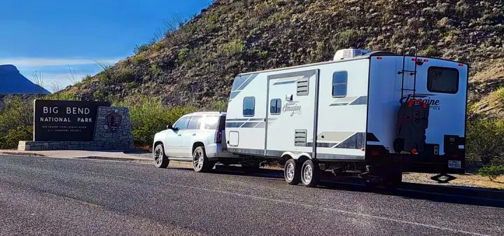 White SUV towing an Imagine travel trailer at Big Bend National Park. Great for an RV rental adventure!. Grand Design Imagine XLS 2021