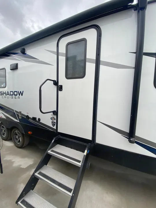 Side view of a "Shadow Cruiser" travel trailer for RV rental, featuring exterior door, steps, and wheels.. Cruiser RV Shadow Cruiser 2022