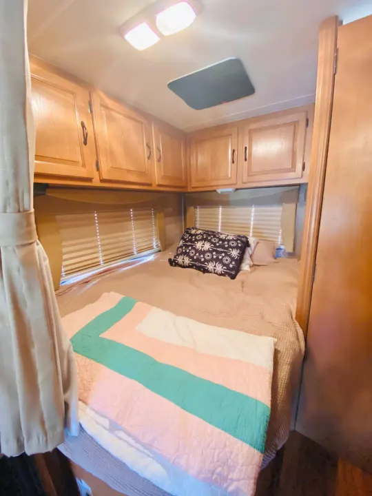 Cozy RV rental bedroom featuring a comfortable bed, wood cabinets, and an overhead skylight.. Forest River Coachmen Prism 2014