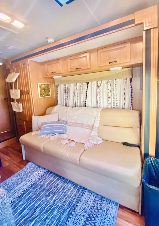 Inside a stylish **rv rental**: light couch, blue patterned rug, and Bohemian curtains. Warm and inviting living space.. Forest River Coachmen Prism 2014