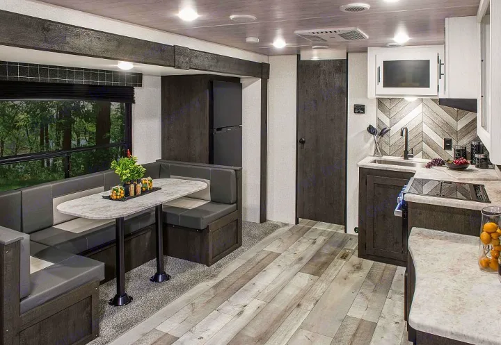 Modern RV rental interior with dinette, full kitchen, and scenic window view of a forest. Comfort on the road.. Sportsmen SE 2023