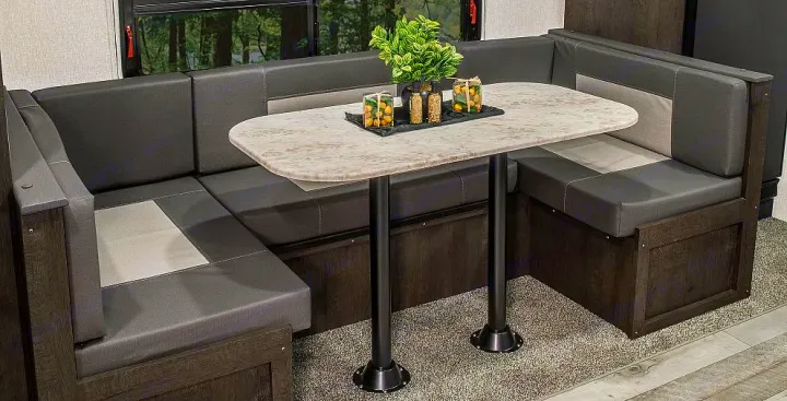 RV rental dinette: U-shaped bench seating in dark/light grey with a speckled table on a carpeted floor, ideal for meals.. Sportsmen SE 2023