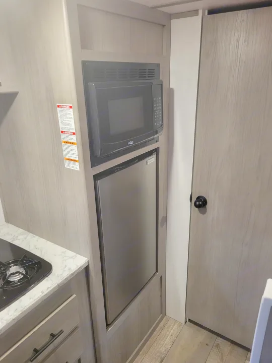 RV rental: Compact kitchen featuring a microwave, mini-fridge, stovetop, and light wood cabinetry.. Coleman Coleman Lantern 17B 2024