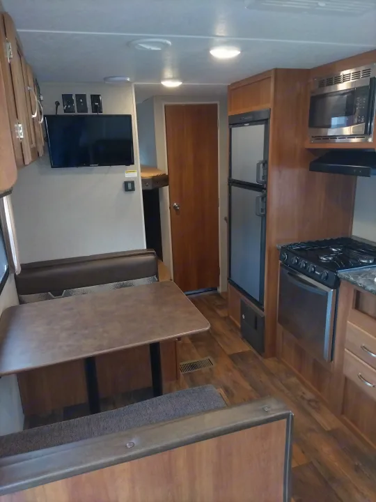 Cozy RV rental interior: dinette, full kitchen, TV, and bunks. Perfect for mobile living.. Keystone RV Springdale Eco-Lite 2018