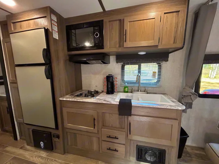 Well-equipped RV rental kitchen featuring a fridge, microwave, stovetop, and coffee maker for your travels.. Gulf Stream Ameri-Lite 2022