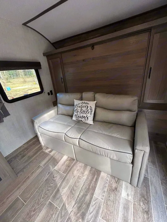 Comfortable RV rental interior with a gray sofa, wood-look floor, and a large window view.. Gulf Stream Ameri-Lite 2022