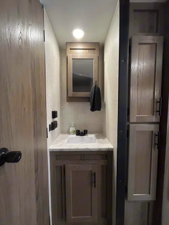 An RV rental interior shows a modern, compact bathroom vanity with a sink, mirror, and organized storage.. Gulf Stream Ameri-Lite 2022