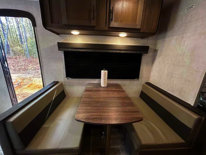 RV rental dinette interior: Modern booth seating, table, overhead cabinets, and a window view. Ideal for camper meals.. Gulf Stream Ameri-Lite 2022