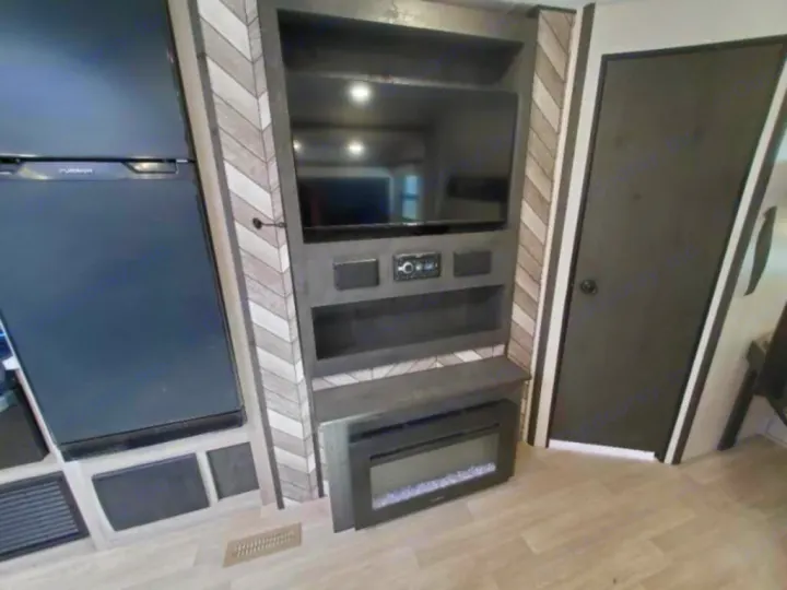 Modern RV rental interior: black fridge, wall-mounted TV, media unit, electric fireplace, and dark door.. KZ Connect C291BHK 2023