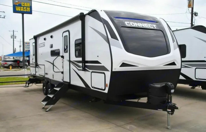 Modern white & black 'Connect' travel trailer RV, an excellent option for an RV rental. Features an awning & steps, parked outdoors.. KZ Connect C291BHK 2023