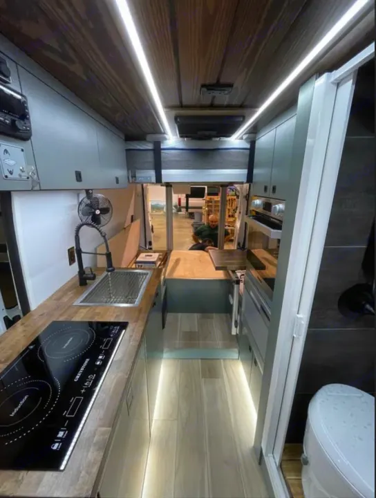 Sleek RV rental interior: kitchen with induction hob, overhead bed, and discreet bathroom. Ready for adventure.. 27North 27North Class B 2023