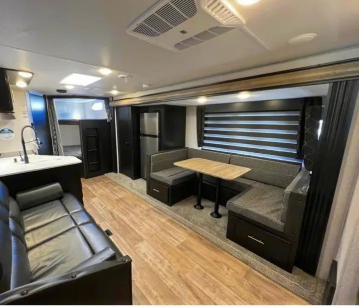 Spacious RV rental interior: kitchen, dining area with dinette, comfy sofa, and bunk beds.. Forest River Cherokee 2022
