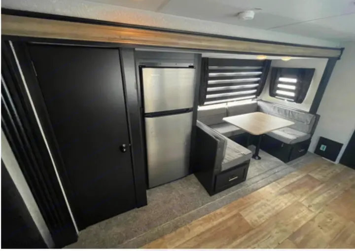 Inside an RV rental: a modern U-shaped dinette, stainless steel refrigerator, and wood-look flooring. Ready for adventures!. Forest River Cherokee 2022