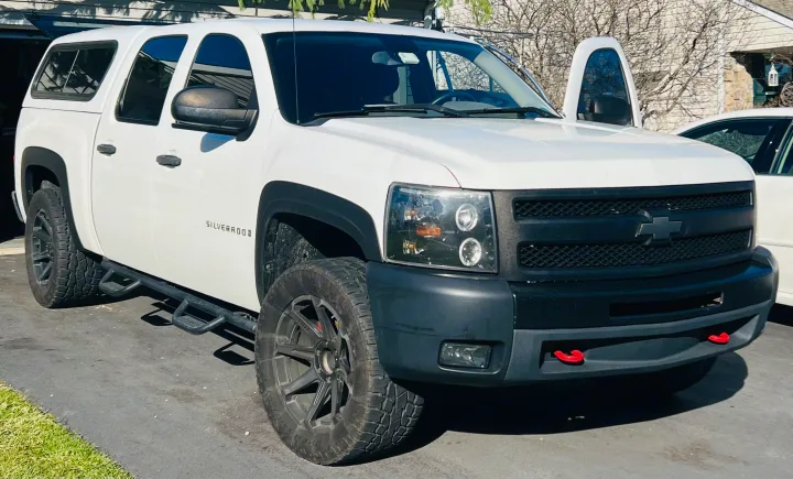 White Chevrolet Silverado pickup truck with a white camper shell, resembling a compact RV rental, parked on an asphalt driveway.. Chevrolet Silverado 1500 2009