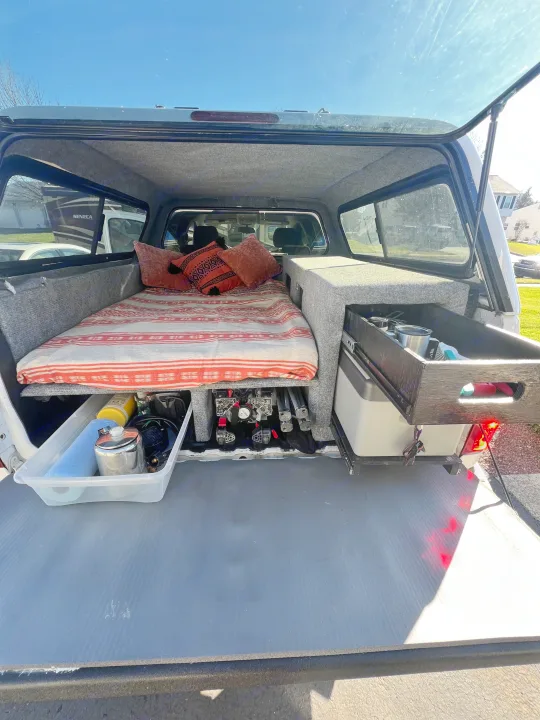 A cozy truck bed camper for adventure, featuring a bed, organized storage, and a pull-out kitchen drawer. Perfect for an RV rental trip!. Chevrolet Silverado 1500 2009
