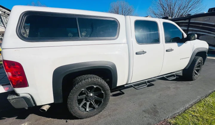 White pickup truck with topper, parked beside an RV rental for your next adventure.. Chevrolet Silverado 1500 2009