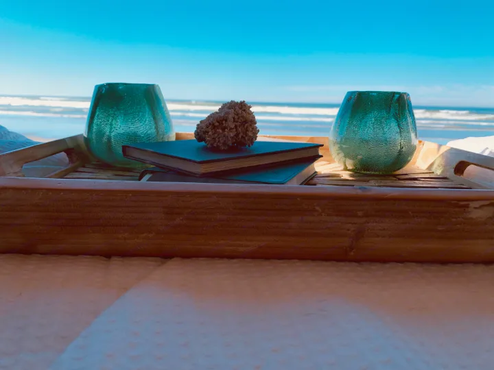 RV rental comfort: A wooden tray with books, teal glass, & coral overlooks the tranquil ocean, perfect for a peaceful retreat.. Winnebago Revel 2022