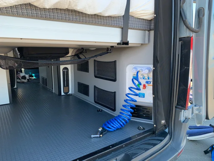 RV rental interior: organized storage, water station with blue hose, durable flooring, and a cozy spot for a dog.. Winnebago Revel 2022