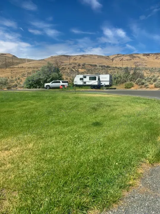 Scenic rv rental: White SUV & travel trailer at a grassy site with arid mountains under a blue sky.. Winnebago 2301BHS 2022