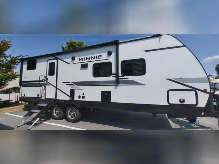 A white "Minnie" travel trailer with black accents and extended steps, parked outdoors, ideal for rv rental.. Winnebago 2301BHS 2022