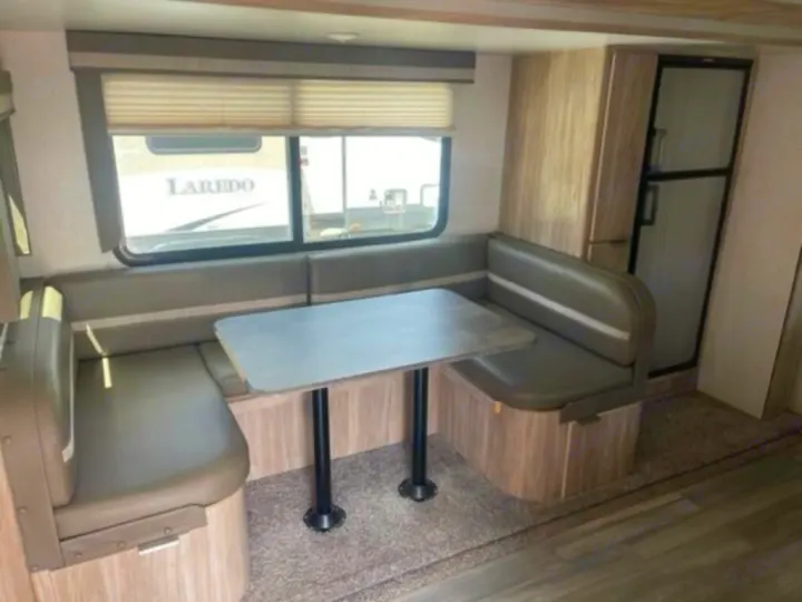This RV rental interior features a spacious U-shaped dinette with a table, plus a refrigerator, perfect for travel.. Winnebago 2301BHS 2022