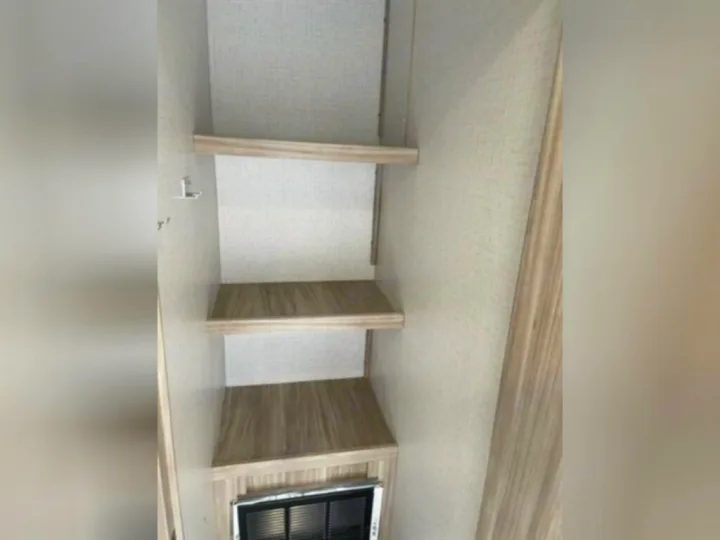 RV rental interior: A narrow closet with three light wood shelves and a vent below offers essential storage.. Winnebago 2301BHS 2022
