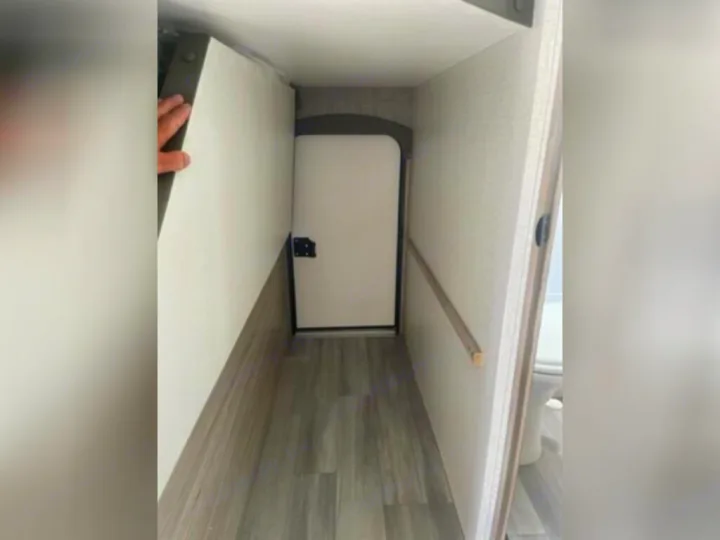 RV rental: Narrow interior passage showing a fold-down panel, a door, and wood-look flooring, optimizing compact living.. Winnebago 2301BHS 2022