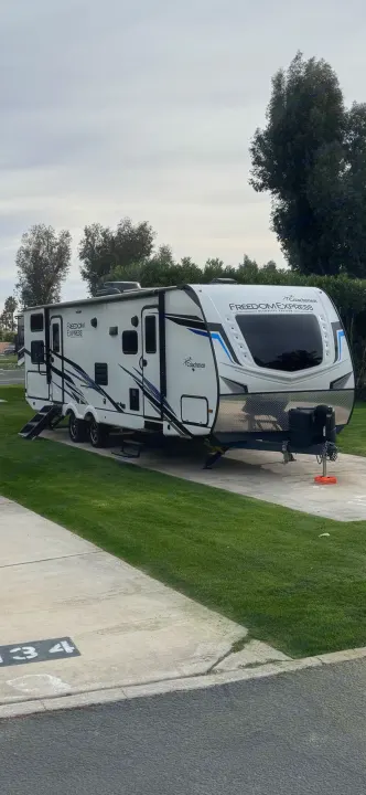 This Coachmen Freedom Express travel trailer, perfect for an RV rental, is parked at a grassy campsite under a cloudy sky.. Coachmen freedom express 287bhds 2022