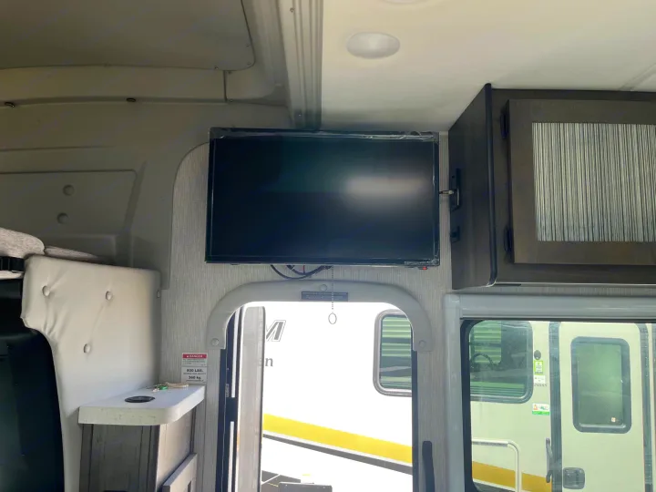 Cozy RV rental interior featuring a wall-mounted TV, cabinetry, and an arched entryway, perfect for your road trip.. Coachmen Prism Elite 2024