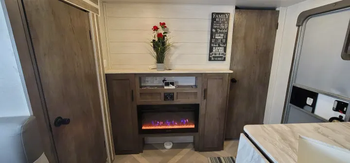 Stylish RV rental interior: electric fireplace, shiplap wall with "Family Rules" sign, and warm wood cabinets.. Forest River Salem Cruise Lite 2021