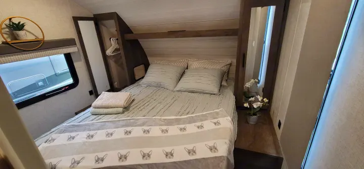 Experience comfort in this RV rental bedroom. It features a cozy bed, window, closet, and a fun dog-patterned blanket.. Forest River Salem Cruise Lite 2021