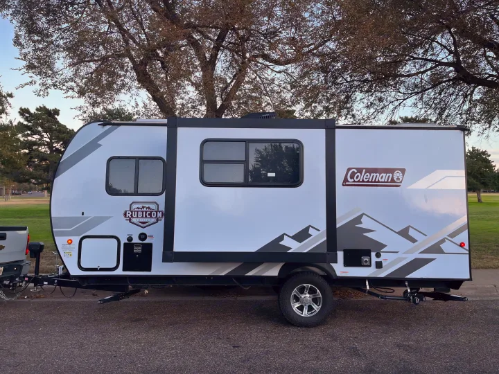 Inside a clean, modern RV rental featuring a kitchen with a sink, oven, microwave, a dinette, and bunk beds.. Dutchmen Coleman Rubicon 2022