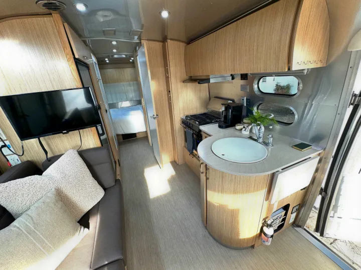 Modern RV rental interior with kitchen, living area, and bedroom visible. Bright and spacious layout.. Airstream Flying Cloud 2017