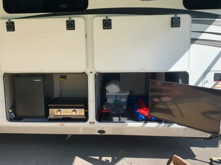 RV rental's outdoor kitchen features a fridge, Blackstone grill, and TV, perfect for camping adventures.. Jayco North Point 2021