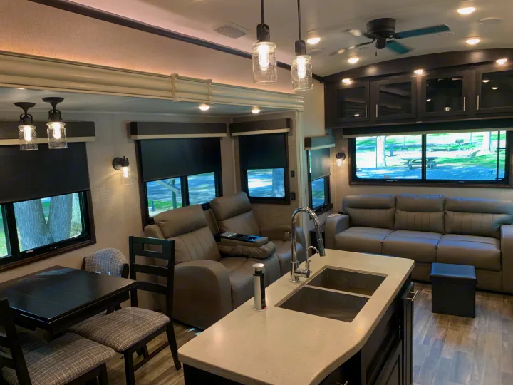Modern RV rental interior with kitchen island, dining table, and comfy recliners, showing spacious living for travelers.. Jayco North Point 2021