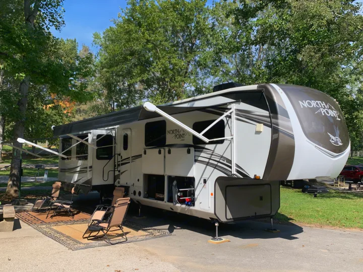 Spacious North Point fifth-wheel RV rental at a sunny campsite with awnings out, rug, & chairs. Perfect for outdoor leisure!. Jayco North Point 2021