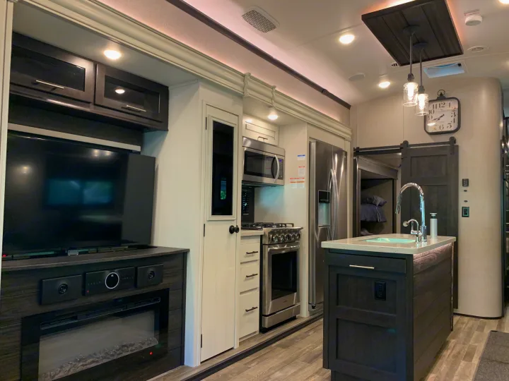 Inside this modern RV rental: a spacious kitchen with island, full-size appliances, TV, & fireplace for comfortable living.. Jayco North Point 2021
