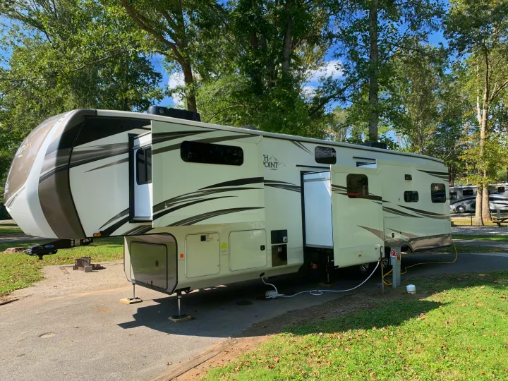 Modern fifth-wheel rv rental set up at a scenic campground with slide-outs extended, ready for a comfortable stay.. Jayco North Point 2021