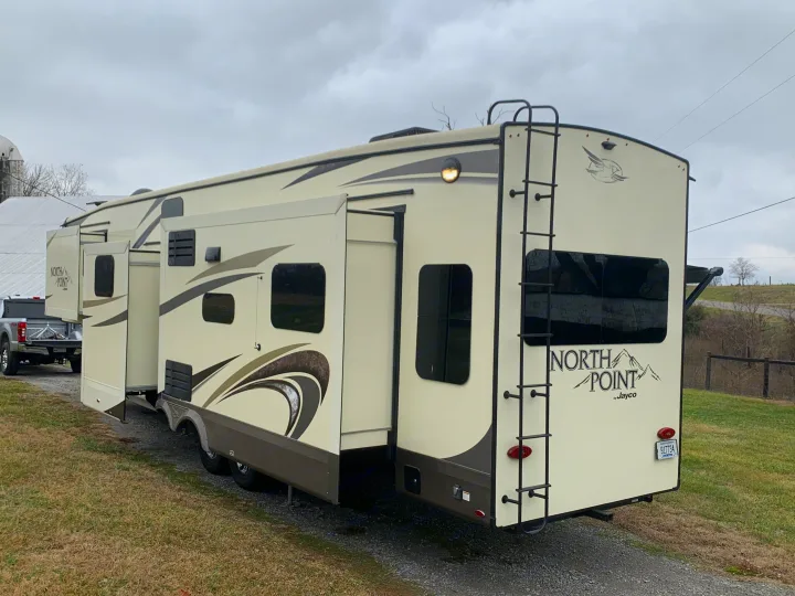 Large North Point by Jayco RV rental with slide-outs extended, parked on gravel in a rural setting under a cloudy sky.. Jayco North Point 2020