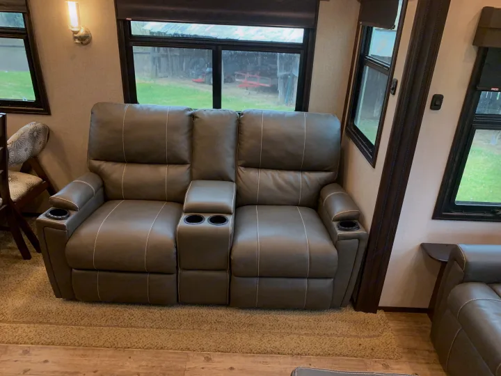Spacious RV rental with a comfortable gray reclining sofa, featuring cupholders for a relaxed travel experience.. Jayco North Point 2020