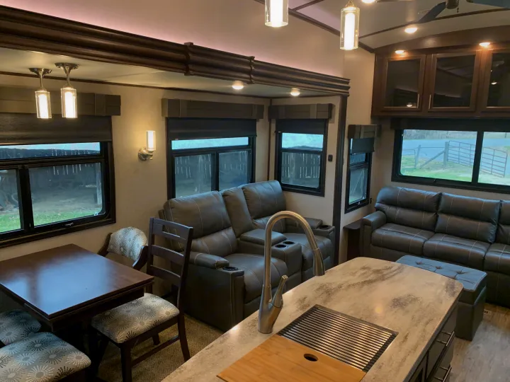 Spacious RV rental living area featuring kitchen island, dining table, and reclining sofas.. Jayco North Point 2020