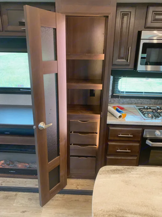 RV rental interior: spacious kitchen area featuring a tall pantry with pull-out drawers, shelves, stove, and microwave.. Jayco North Point 2020